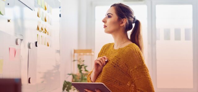 woman using tablet and checking post-it notes