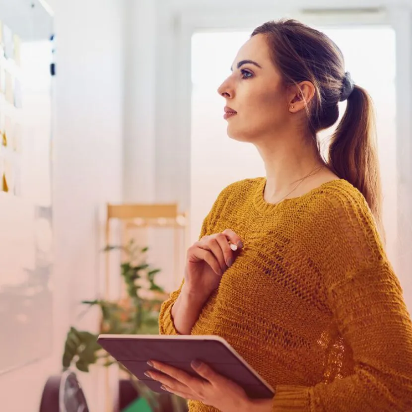woman using tablet and checking post-it notes