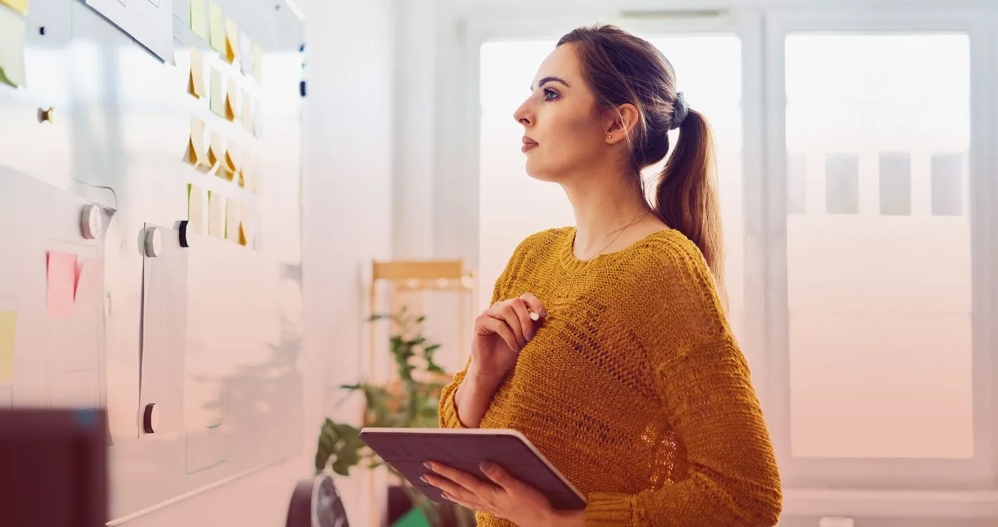woman using tablet and checking post-it notes