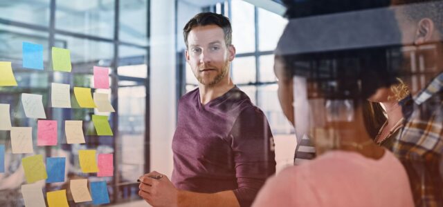 man taking notes on post-it in office