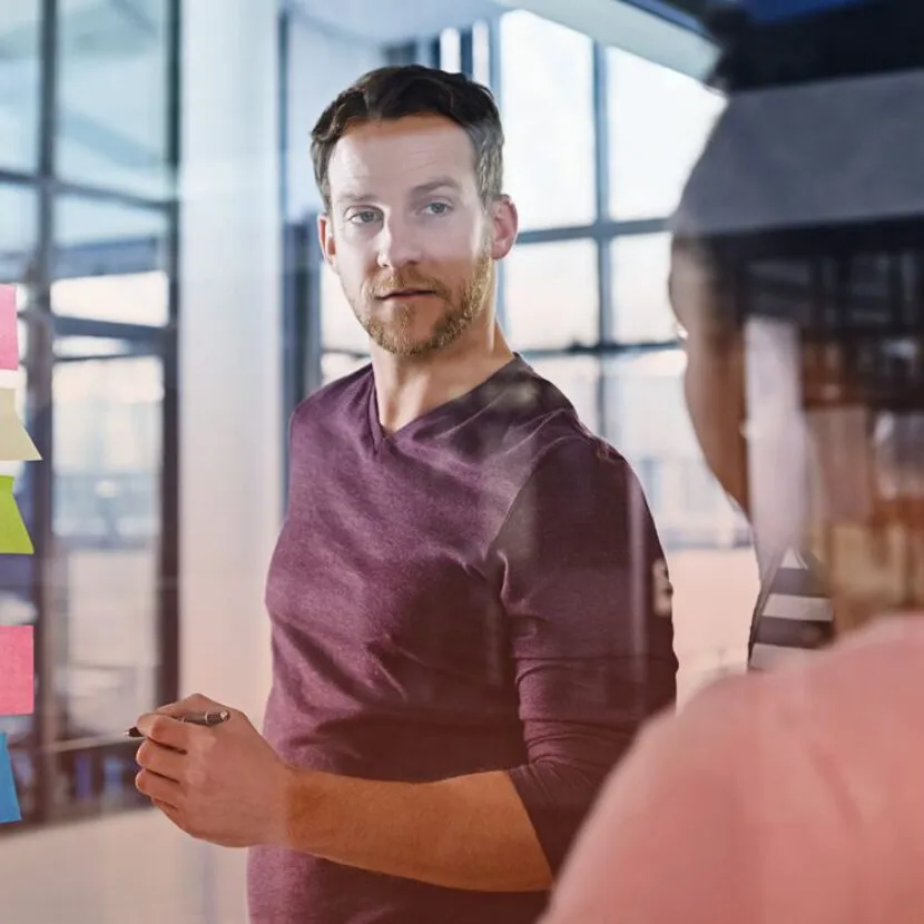 man taking notes on post-it in office