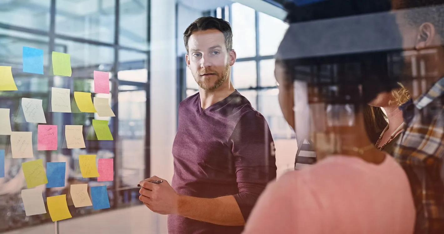 man taking notes on post-it in office