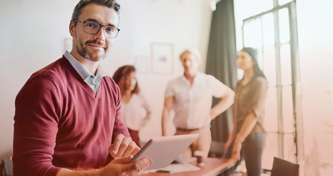 satisfied man with tablet in office with colleagues