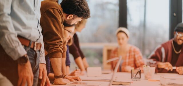 team huddled over laptops in office setting