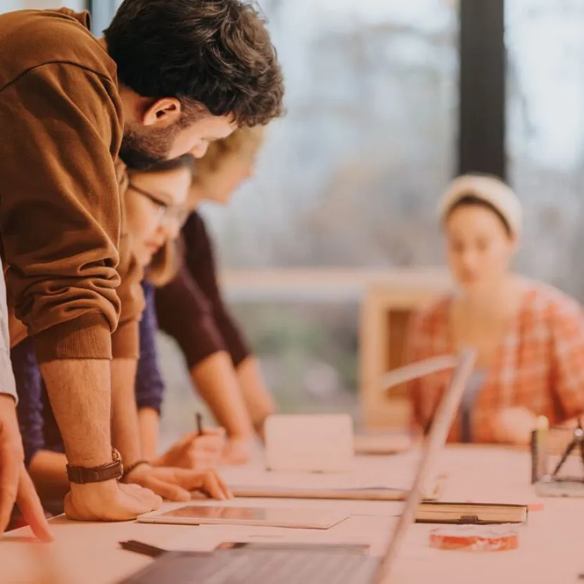 team huddled over laptops in office setting